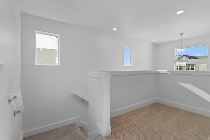 Recessed lighting, multiple windows, neutral carpeting, and white painted walls