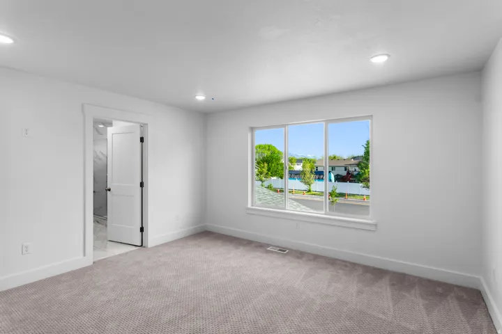 Neutral wall paint, recessed lighting, carpet flooring, large window, and a paneled door