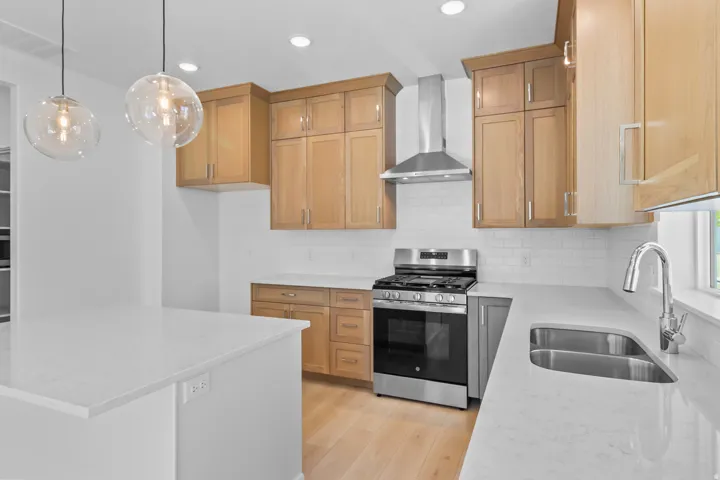 Kitchen featuring light wood-finish cabinetry, stainless steel appliances, a subway tile backsplash, and light-toned countertops