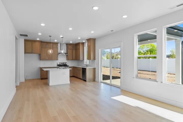 Open-concept living space with light wood-finish flooring, recessed lighting, and large windows