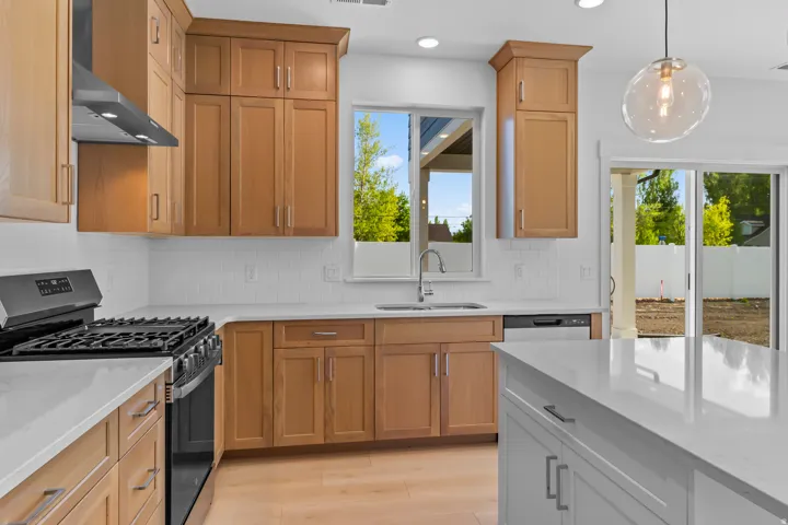 Kitchen featuring light wood-finish cabinetry, white subway tile backsplash, white countertops, and stainless steel appliances