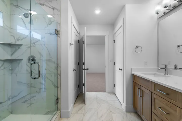 Glass-enclosed shower with tiled walls and built-in shelving