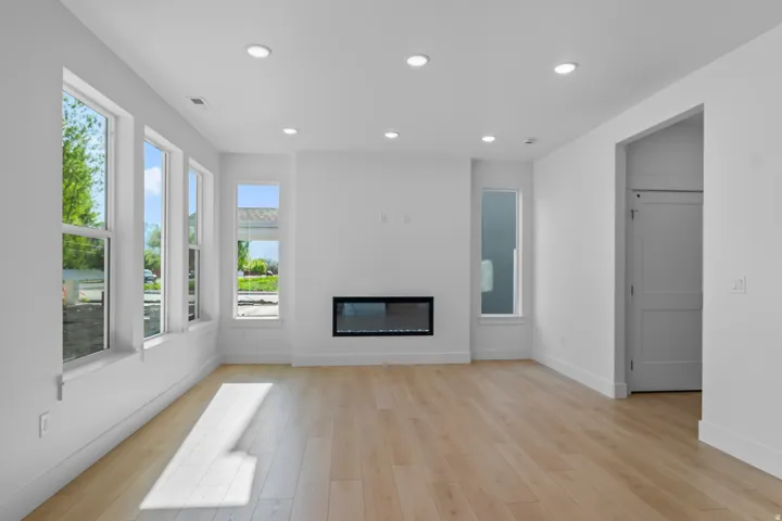 Recessed lighting, wood-finish flooring, multiple windows, built-in fireplace, and a solid panel door
