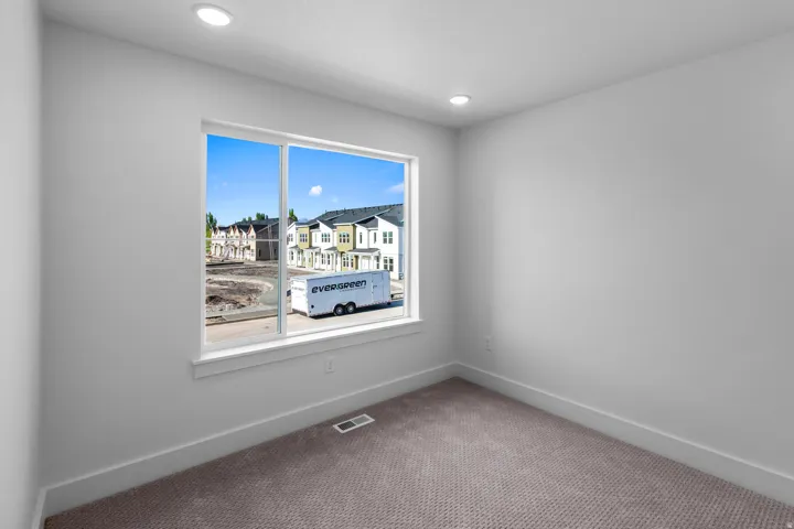 Recessed ceiling lighting, white interior walls, white window trim, and neutral carpeting