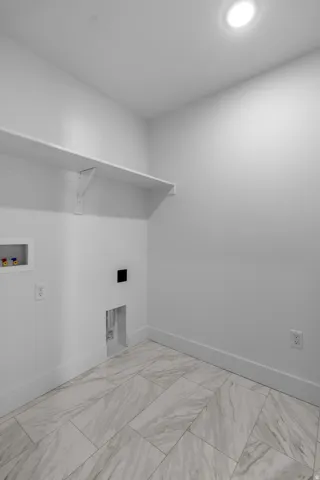 Recessed ceiling lighting illuminates a utility space featuring a built-in white shelf and large format floor tiles