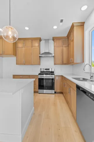 Kitchen featuring light wood-finish cabinetry, white subway tile backsplash, stainless steel appliances, and a central island with a white countertop