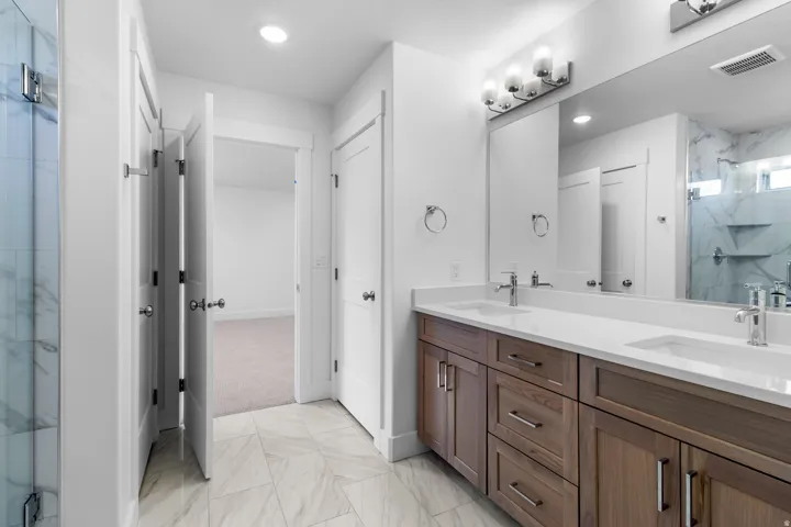 Dual vanity with white countertops, wood-finish cabinetry, and chrome fixtures