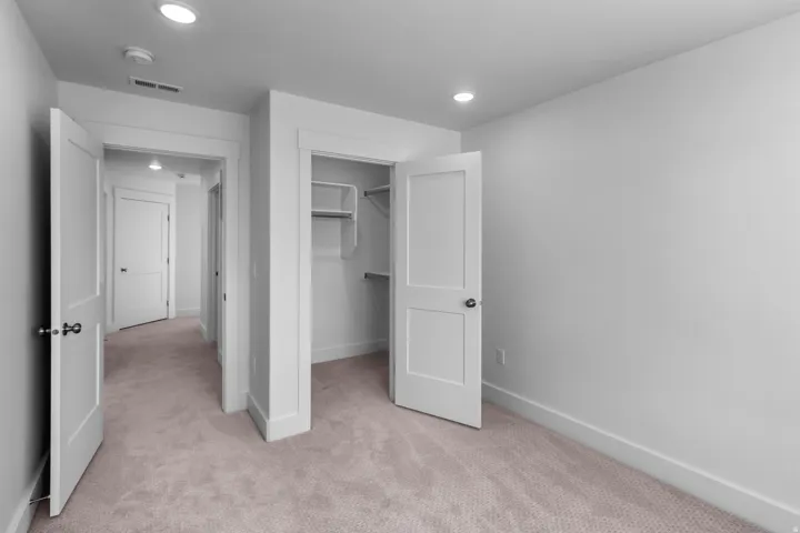 Bedroom featuring light-toned carpeting, white walls, recessed ceiling lighting, and a closet with built-in shelving