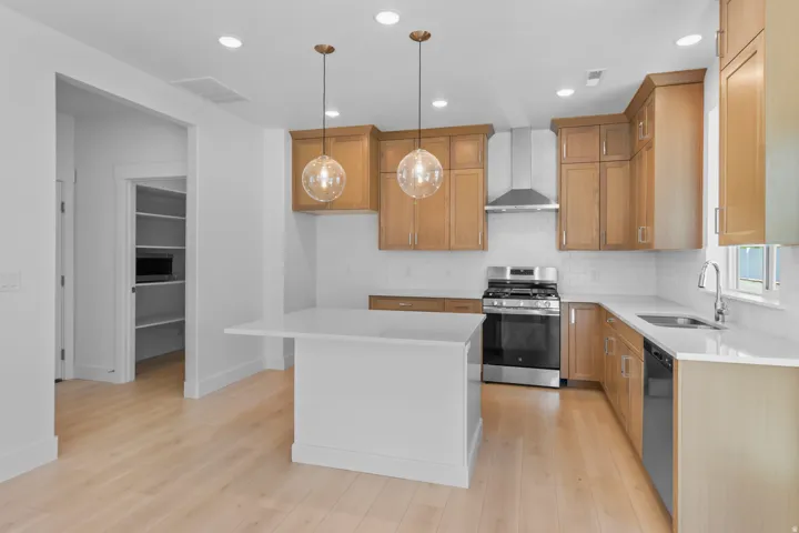 Kitchen featuring a central island with a countertop extension, light wood-finish cabinetry, stainless steel appliances, a subway tile backsplash, and recessed lighting
