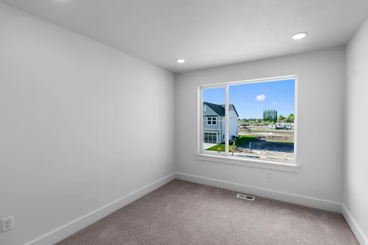 Recessed ceiling lighting, white walls, carpeted flooring, and a large window