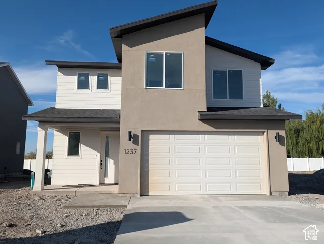 Modern exterior featuring a combination of horizontal siding and stucco finish, a covered entryway, a prominent shed roofline, and an attached two-car garage