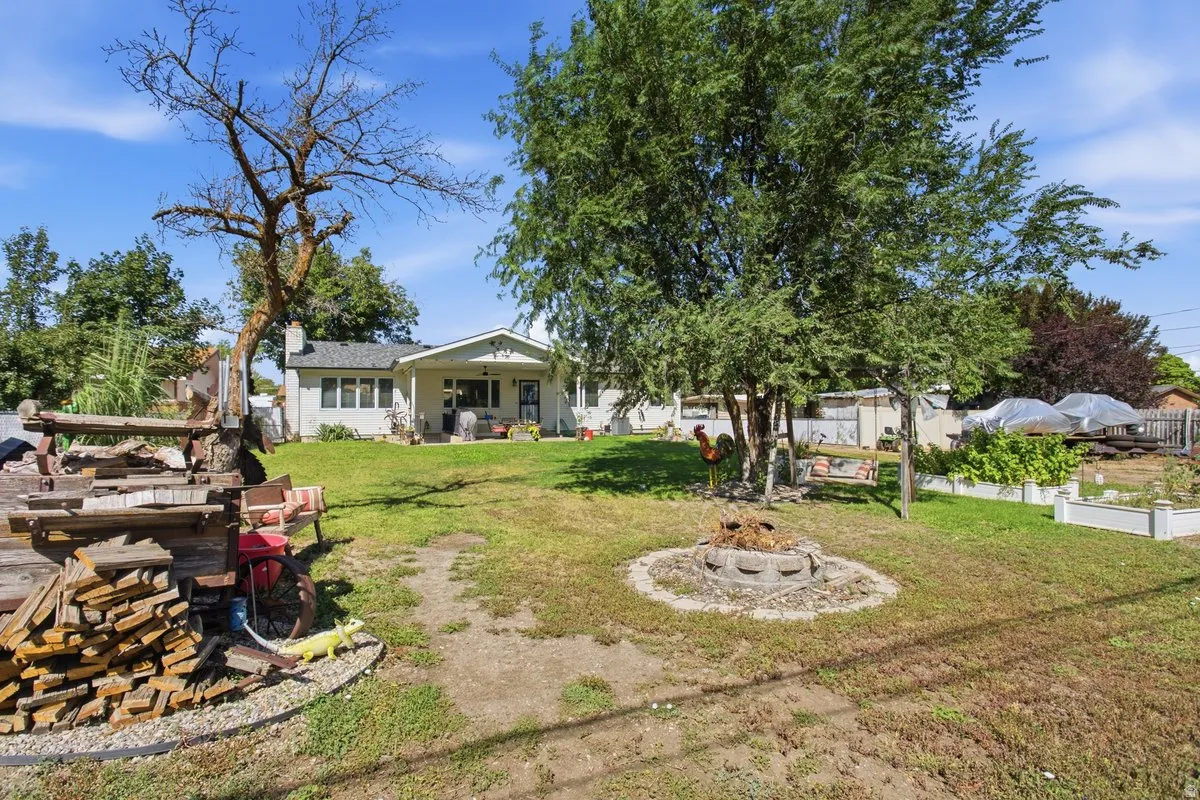 Expansive backyard, .43 acres. Some antiques for sale or negotiable with purchase of home. Features a central fire pit, mature trees, and a raised garden bed