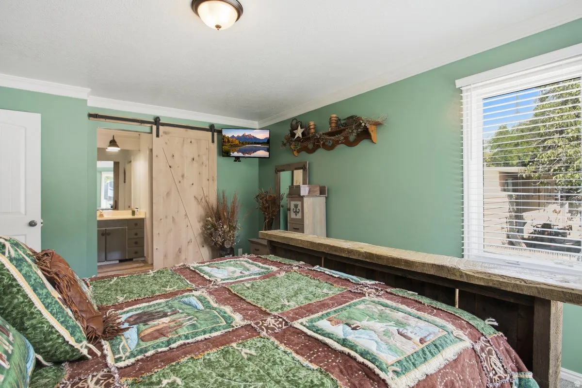 Barn door entry to the owners bathroom, crown molding, and a window with horizontal blinds