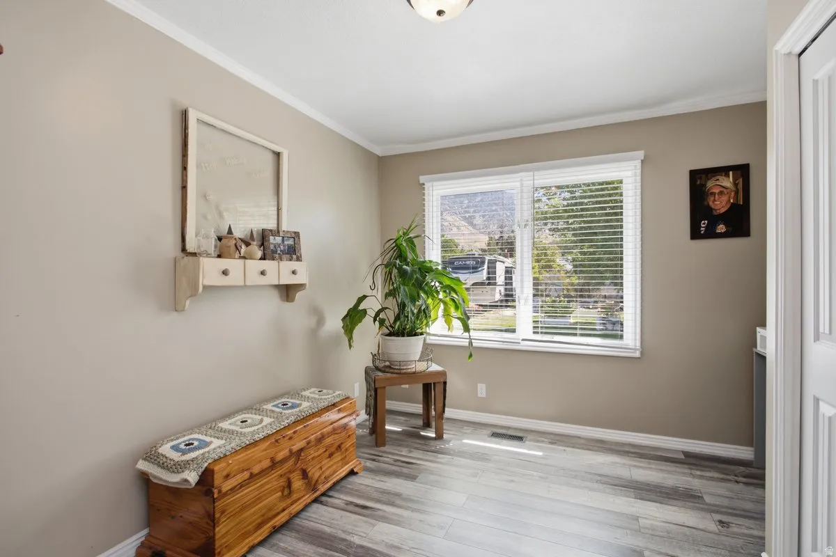 Neutral painted walls, crown molding, wood-finish flooring, and white trim