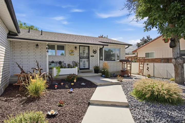 Brick exterior, covered entry, front porch, mature landscaping, and concrete pathway