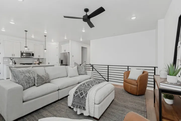 Open-concept living area featuring a modern black ceiling fan with integrated lighting, recessed ceiling lights, and wood-finish flooring