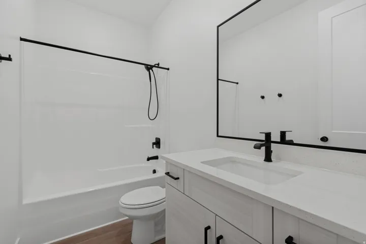 White vanity with a single basin, light-toned countertop, and matte black fixtures