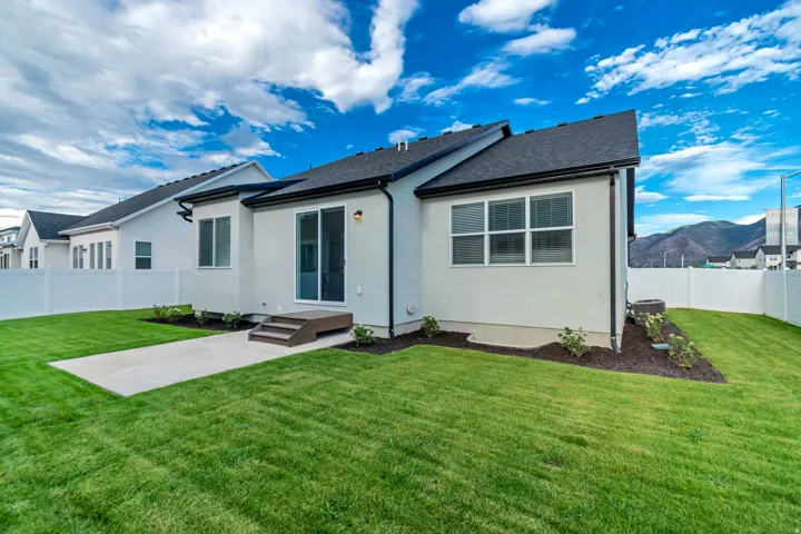 Expansive backyard featuring a manicured lawn, concrete patio, and a privacy fence