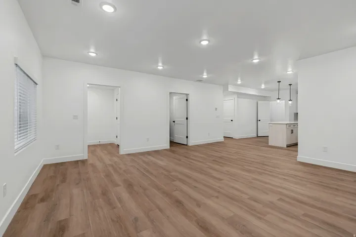 Expansive open-concept room with wood-finish flooring, recessed lighting, and a window with blinds
