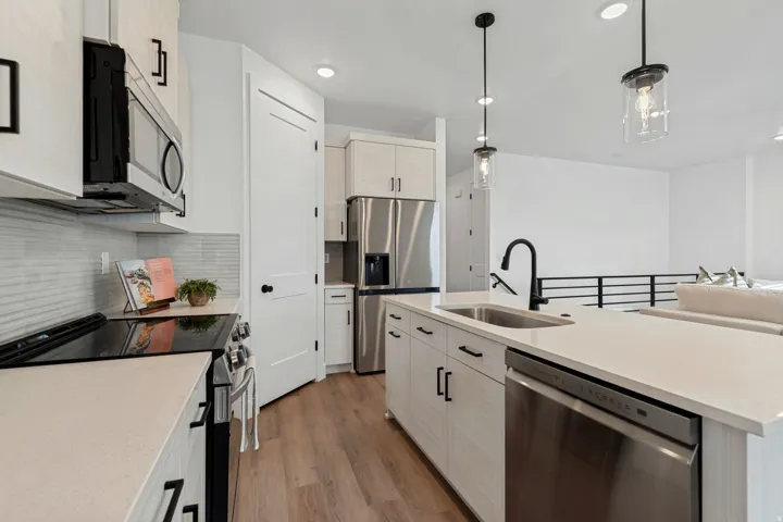 Kitchen featuring white cabinetry, light countertops, wood-finish flooring, and stainless steel appliances