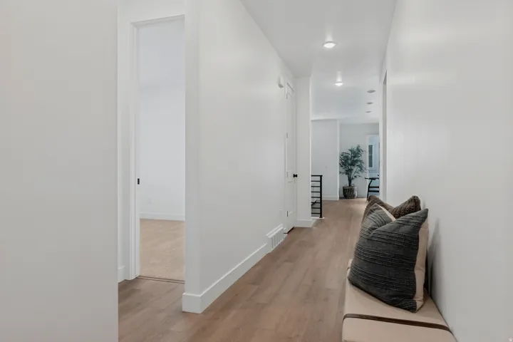 Recessed lighting illuminates the hallway with wood-finish flooring