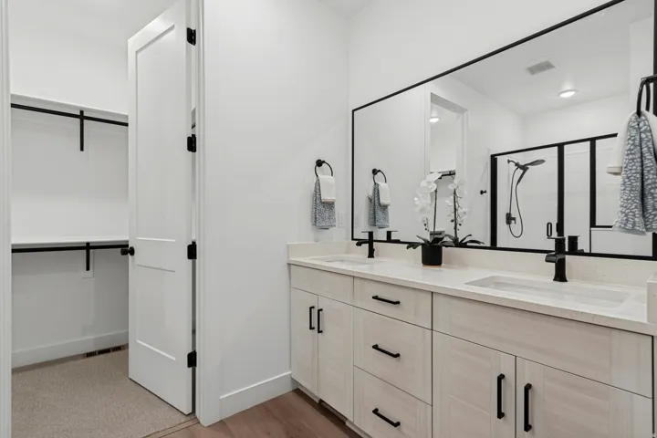 Dual vanity with integrated sinks, light-toned cabinetry, and matte black fixtures