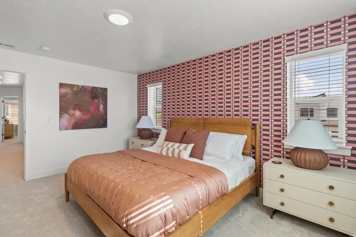 Recessed ceiling lighting, patterned accent wall, single window with blinds, light-colored carpeting, and a doorway opening to an additional room