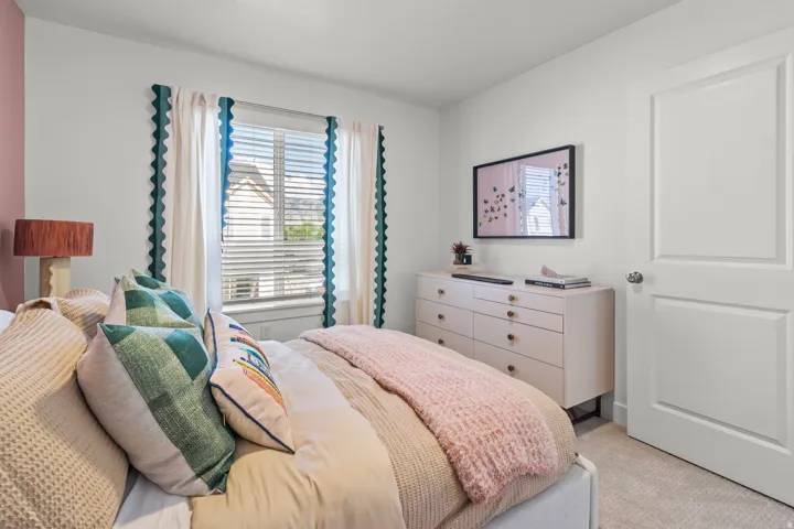 Wall-mounted television with a light-toned dresser, a two-panel interior door with a chrome knob, and a window with blinds