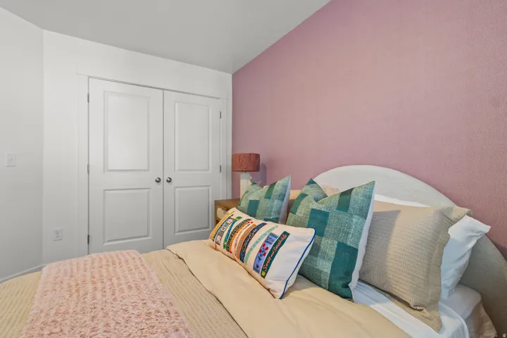 White bi-fold closet doors with panel detailing, textured pink wall, and a curved headboard
