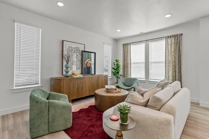 Recessed lighting illuminates this bright space featuring multiple windows with blinds, wood-finish flooring, and a built-in media console