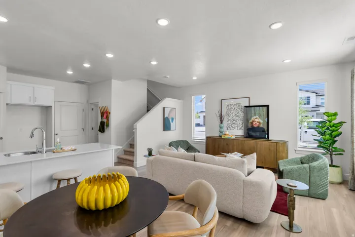 Open-concept living area with light-toned wood-finish flooring, recessed lighting, and white walls
