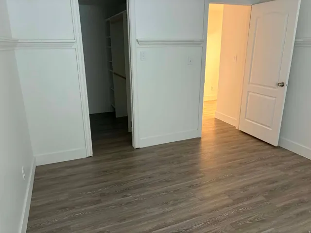 Wood-finish flooring throughout, white baseboards, and built-in closet shelving