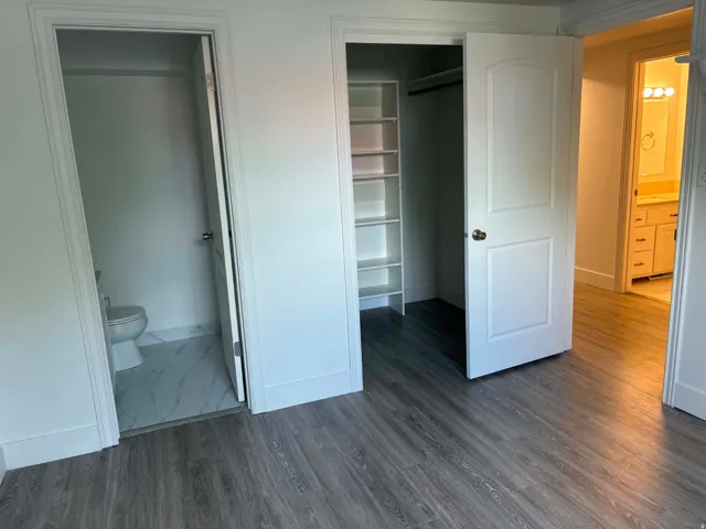 Wood-finish flooring throughout, featuring a built-in closet system with shelving and hanging rod