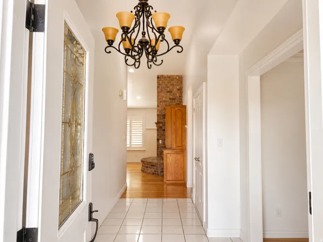 Entryway featuring a decorative glass door, black wrought iron chandelier, and tile flooring