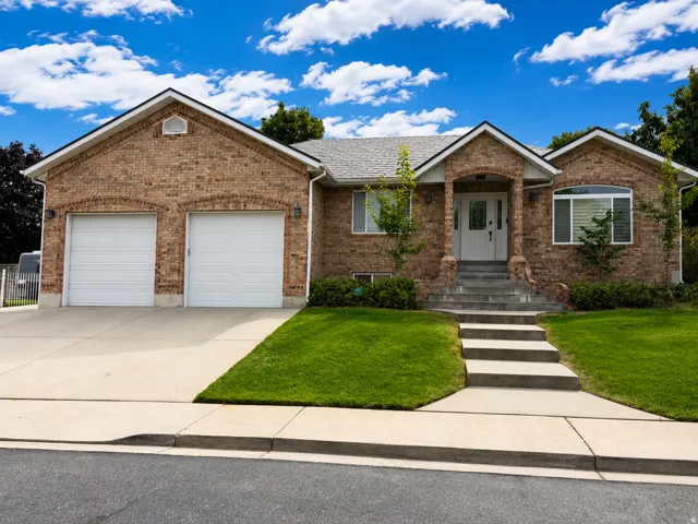 Brick exterior, attached two-car garage, concrete driveway, concrete sidewalk, mature landscaping