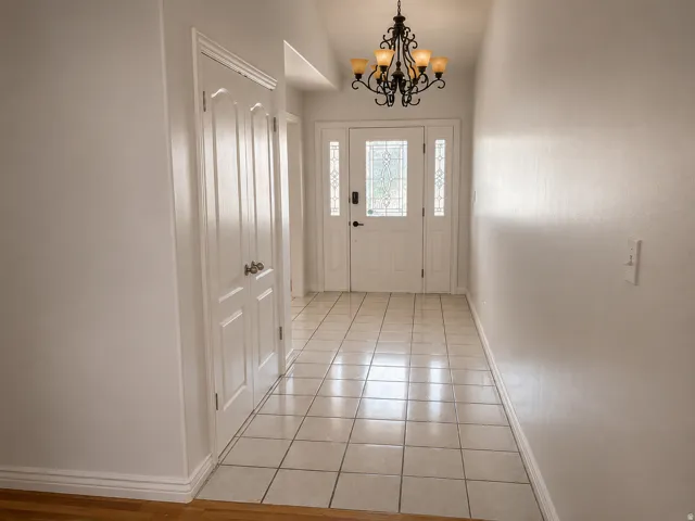 Entryway featuring a decorative chandelier, white paneled doors, tile flooring, and a front door with leaded glass inserts