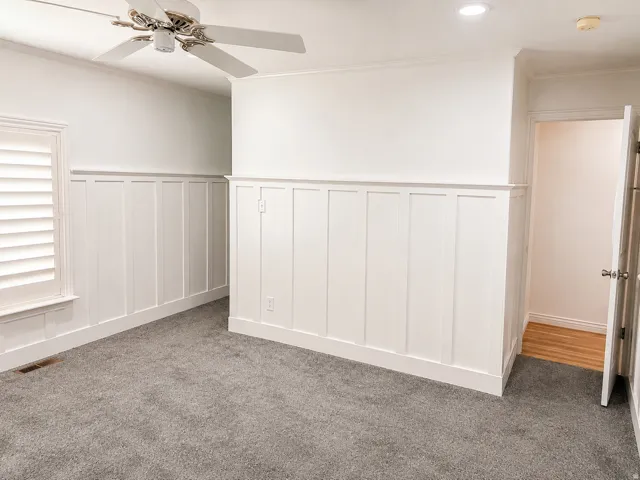 Board and batten wainscoting, ceiling fan, recessed lighting, white window shutters, and gray carpeting