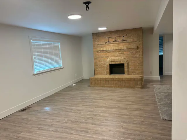 Living area featuring wood-finish flooring, a brick fireplace, and recessed lighting