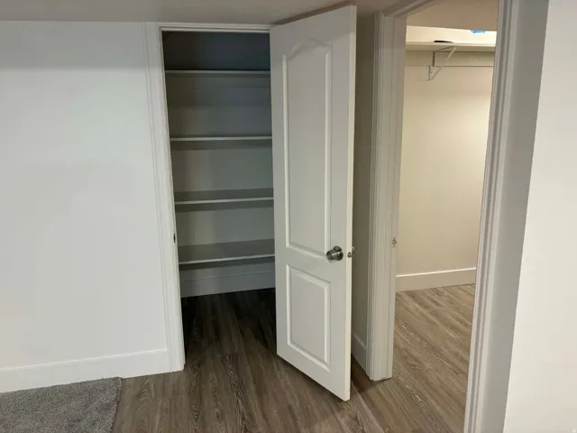 Wood-finish flooring, white walls, and a white two-panel door with a brushed nickel doorknob