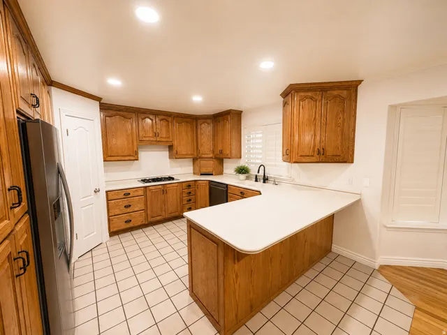 Full kitchen featuring wood cabinetry, white countertops, a built-in gas cooktop, and a stainless steel refrigerator