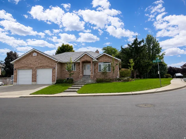 Brick exterior residence with an attached two-car garage, front entry steps, and established landscaping
