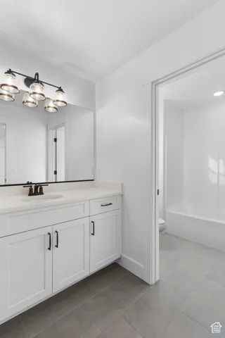 White shaker-style vanity with a light-toned countertop, under-mount sink, and bronze-finish faucet