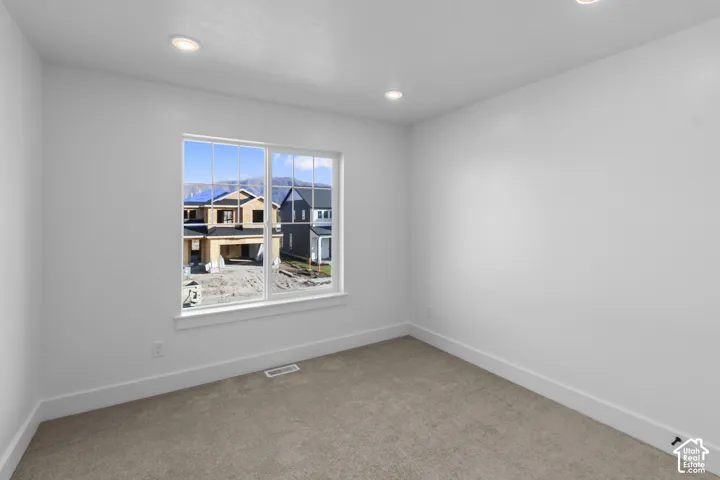 Neutral tone carpeting with white walls and recessed ceiling lighting