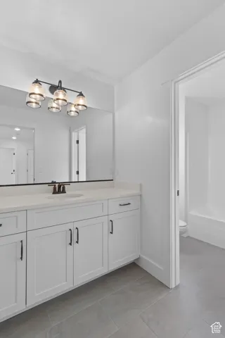 Double vanity with white cabinetry, a light-toned countertop, and a large mirror