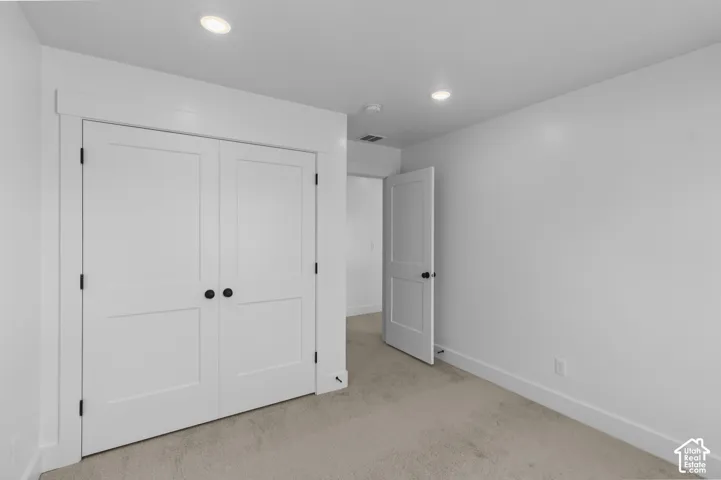 Recessed lighting, white walls, light-colored carpeting, white trim, and white paneled doors with black hardware