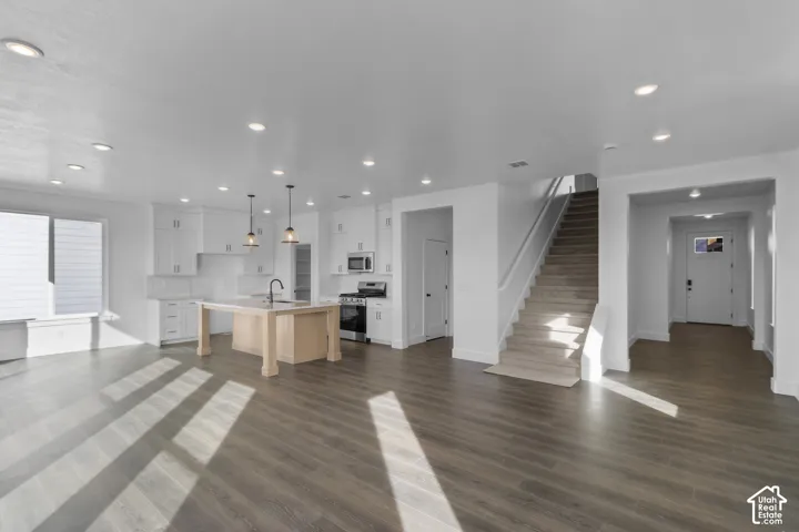 Open-concept living space with wood-finish flooring, recessed lighting, and a modern kitchen island