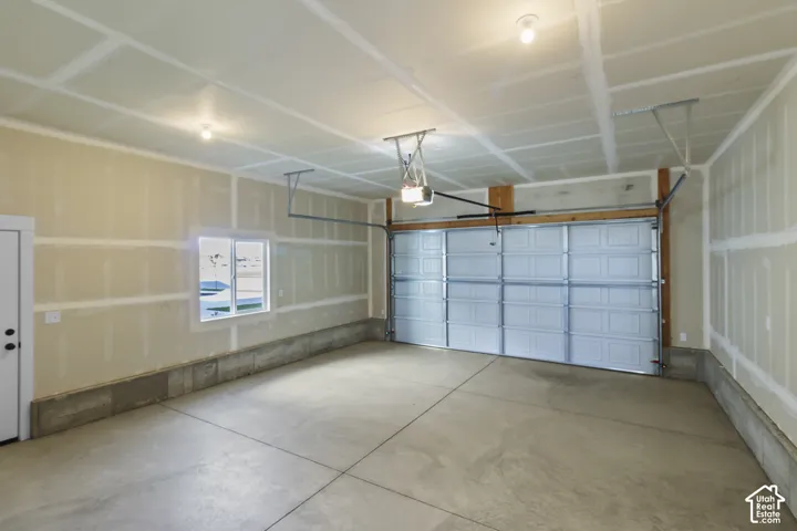 Spacious garage with an overhead door, smooth concrete flooring, and a single window