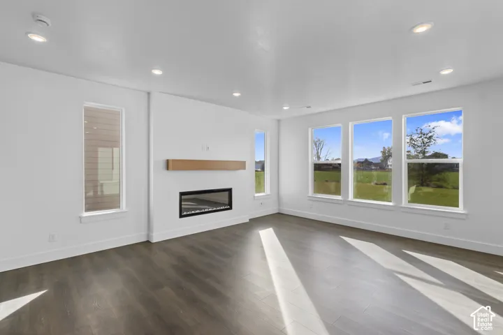 Dark wood-finish flooring, recessed lighting, and a linear electric fireplace with a wood mantle