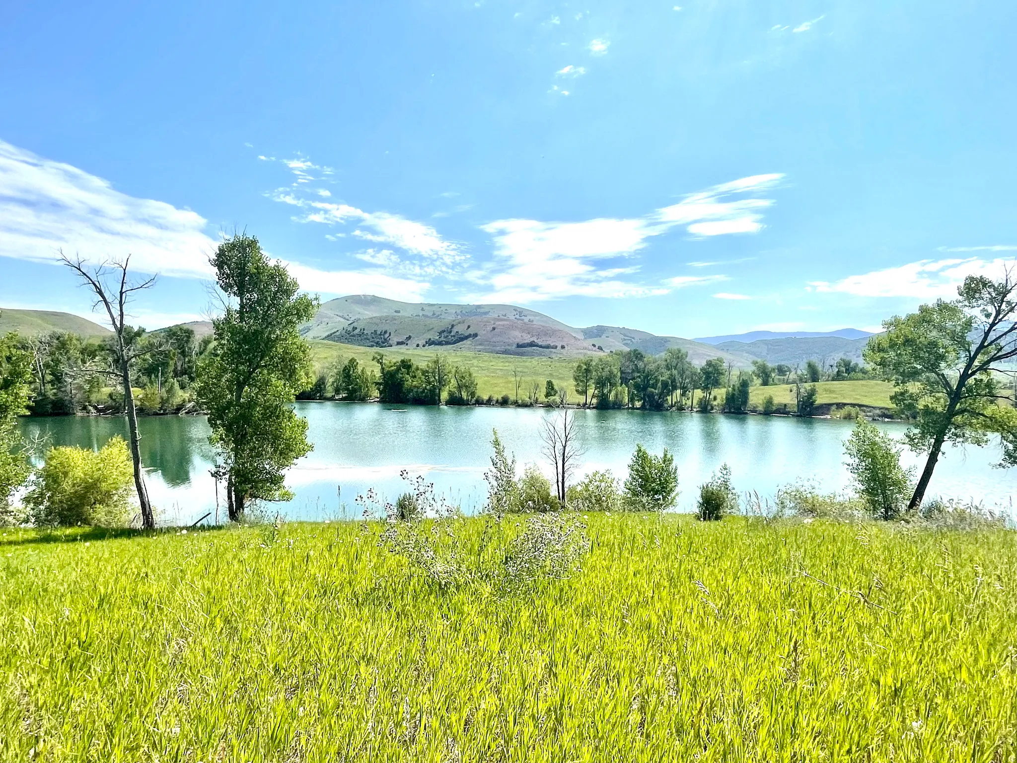 Expansive green landscape with a large body of water, bordered by verdant hills and distant mountains