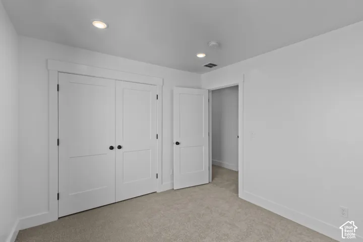 Recessed ceiling lighting, white interior doors with matte black hardware, neutral carpeting, and white wall finishes